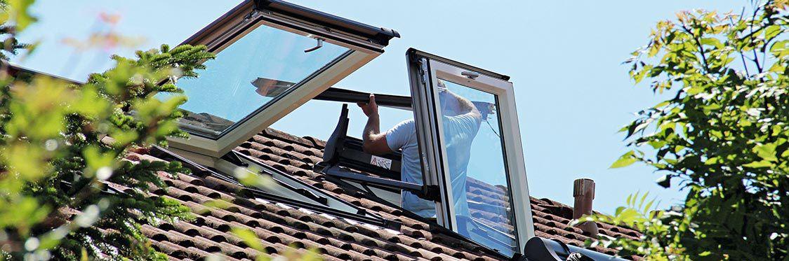 Een ambachtsman die de ramen op het dak installeert
