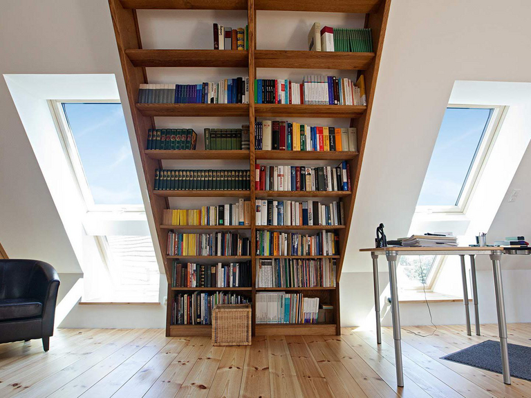 Boekenkast op een zolderappartement met dakraam in tandeminstallatie