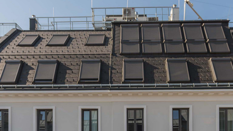 Dach mit mehreren Dachfenstern, die geschlossene Außenrollladen haben